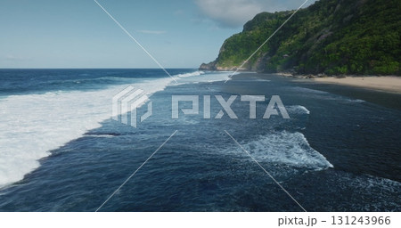 Ocean waves crashing on Nyang Nyang black sand beach, Bali, lush green cliffs in background, creating breathtaking tropical paradise scene. Stunning aerial view of beautiful nature, travel background 131243966
