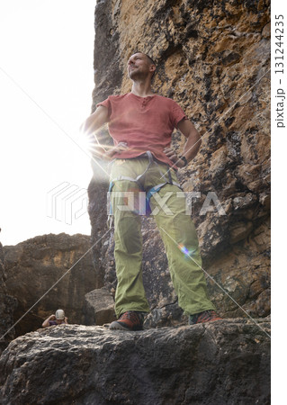 Man rock climber standing on cliff top enjoying successful climb Man rock climber standing on cliff top enjoying successful climb 131244235