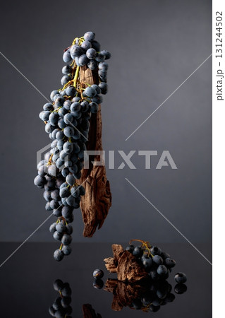 Blue grapes and weathered snags on a black reflective background. 131244502