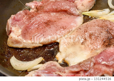 A close-up of marinated meat being fried with onions and vegetable oil in a frying pan. A close-up of marinated meat being fried with onions and vegetable oil in a frying pan. 131244516