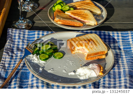 Close-up of a breakfast plate featuring toasts topped with fried eggs, tomatoes, and cucumbers. Ideal for lifestyle, food photography, and cozy morning scenes. 131245037