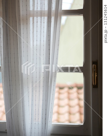 White curtain with a gold handle is hanging in front of a window White curtain with a gold handle is hanging in front of a window 131245614