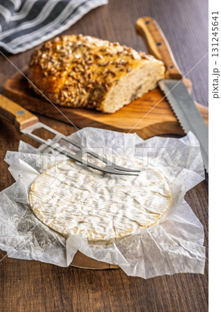 Camembert cheese on wrapping paper. French cheese with mold on the surface. Camembert cheese on wrapping paper. French cheese with mold on the surface. 131245641