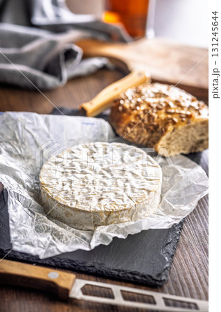 Camembert cheese on wrapping paper. French cheese with mold on the surface. 131245644