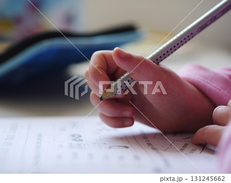 Child is writing with a pencil on a piece of paper Child is writing with a pencil on a piece of paper 131245662