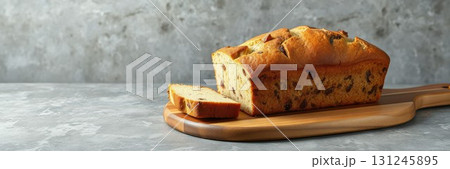 Freshly baked loaf of bread on a wooden cutting board surrounded by a rustic kitchen setting 131245895