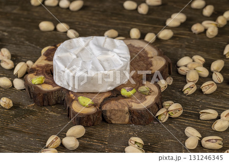 whole cheese in white mold, delicious white soft cheese in mold and a large number of salted pistachios with cracked shells. whole cheese in white mold, delicious white soft cheese in mold and a large number of salted pistachios with cracked shells. 131246345