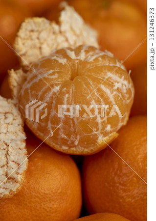 tangerines are stacked together, a large number of ripe orange tangerines are on the table and several peeled tangerines are on top 131246373