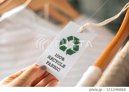 Eco clothing tag with recycle fabric symbol on clothes hanger for sustainable fashion 131246668