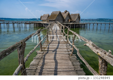 an old wooden bridge leading to a wooden bungalow on stilts across the lagoon 131246945