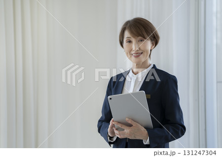 タブレットを持ったカメラ目線の50代のビジネスウーマン 131247304