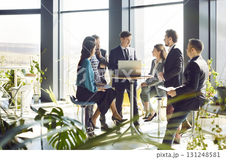 Group of business people relaxing in lobby listening to businessman Group of business people relaxing in lobby listening to businessman 131248581