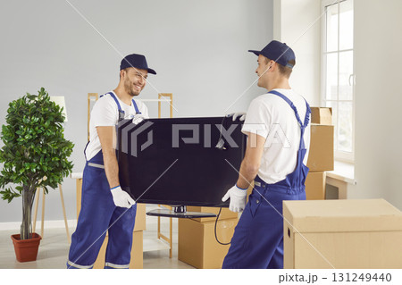 Two Movers Delivering Television during Home or Office Relocation Two Movers Delivering Television during Home or Office Relocation 131249440