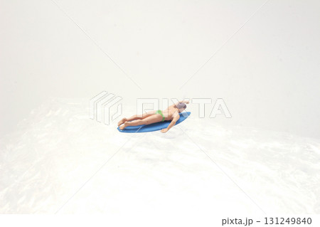 Miniature Surfer Figure On Green Surfboard Over Clear Surface 131249840