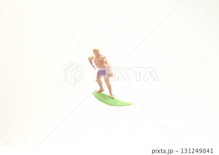 Miniature Surfer Figure On Green Surfboard Over Clear Surface Miniature Surfer Figure On Green Surfboard Over Clear Surface 131249841