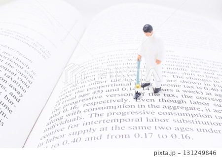 Miniature Man On Open Book: Economics And Tax Imagery Miniature Man On Open Book: Economics And Tax Imagery 131249846