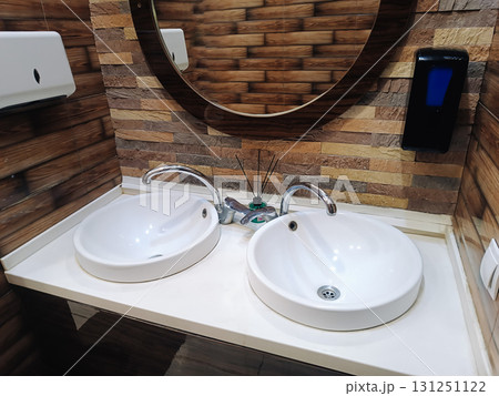 modern bathroom interior with two sinks, a faucet and a round mirror 131251122