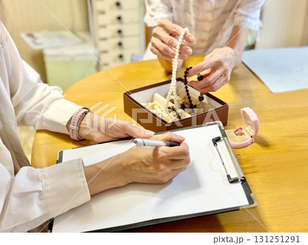 箱に入ったアクセサリーを持つ高齢女性と用紙に記入する女性 131251291