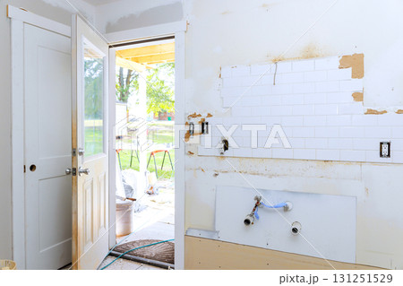 Bare walls exposed plumbing, room renovation door opens to sunny outdoor space. 131251529