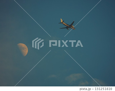 青空に浮かぶ白い月を背景に飛ぶ旅客機 青空に浮かぶ白い月を背景に飛ぶ旅客機 131251810
