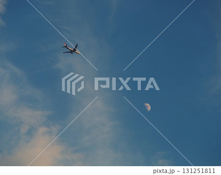 青空に浮かぶ白い月を背景に飛ぶ旅客機 青空に浮かぶ白い月を背景に飛ぶ旅客機 131251811