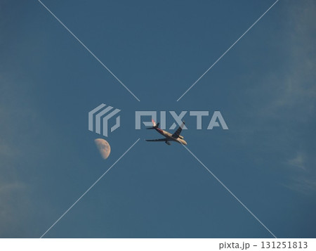 青空に浮かぶ白い月を背景に飛ぶ旅客機 青空に浮かぶ白い月を背景に飛ぶ旅客機 131251813