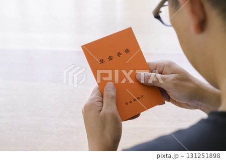 年金手帳を見つめる男性 131251898
