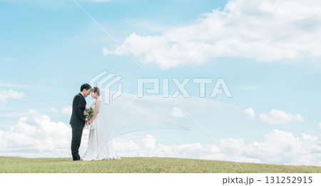 ベールをなびかせる空バックの新郎新婦(ウェディング・結婚式・ブライダル・フォトウェディング) ベールをなびかせる空バックの新郎新婦(ウェディング・結婚式・ブライダル・フォトウェディング) 131252915