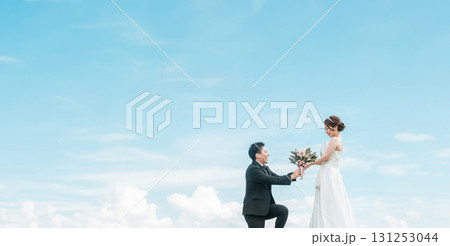 跪いて花束を渡す新郎とドレス姿の新婦（ウェディング・結婚式・ブライダル・フォトウェディング） 131253044