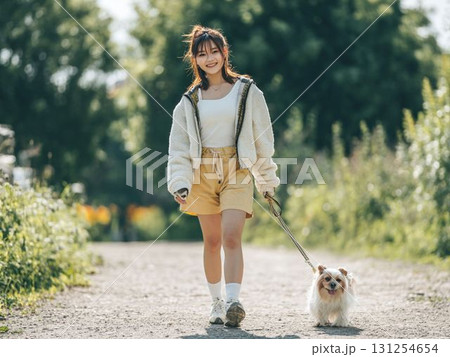 公園を散歩する女性と小型犬 公園を散歩する女性と小型犬 131254654