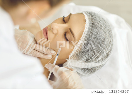Female cosmetologist making rejuvenation anti wrinkle injection in woman face skin in beauty salon. 131254897