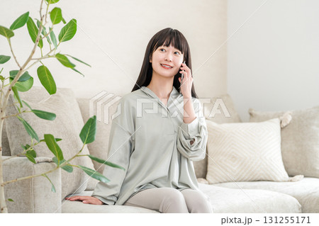スマホで電話する日本人女性(家・ソファ・笑顔) スマホで電話する日本人女性(家・ソファ・笑顔) 131255171