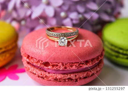 Engagement ring on macaron and flowers background 131255297