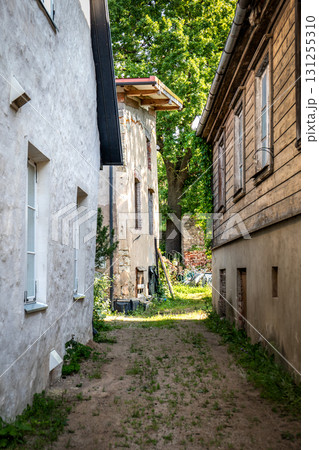 Narrow Alleyway Between Old Rustic Houses with Overgrown Path Narrow Alleyway Between Old Rustic Houses with Overgrown Path 131255310