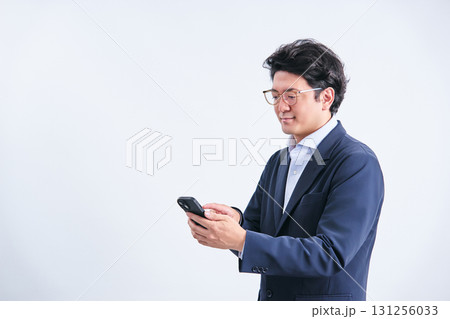 白バックの前でスマホを検索する30代の会社員の男性 白バックの前でスマホを検索する30代の会社員の男性 131256033