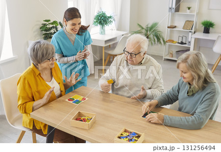 Elderly people solving puzzle with caregiver, enjoying mental stimulation and social interaction. 131256494