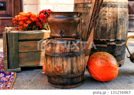 Copper cauldron on old wooden barrel, box, pumpkins in autumn yard. 131256967