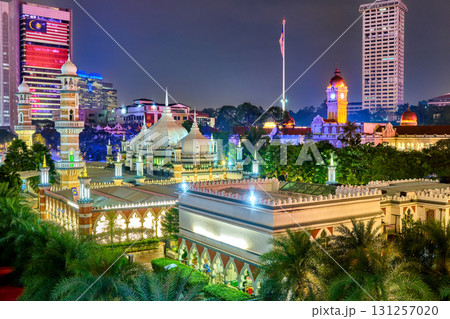 Colorful cityscape at night with brightly illuminated Jamek Mosque and Sultan Abdul Samad Building with clock tower. High-rises, Malaysian flag, modern contrast, traditional culture, architecture 131257020