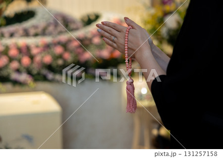 葬儀場で手を合わせて拝む若い女性の手元 131257158