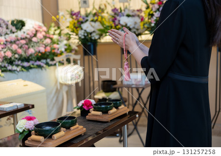 葬儀場で手を合わせて拝む若い女性 131257258