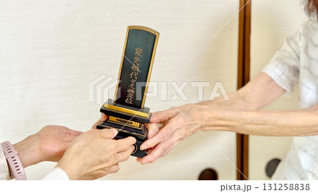 高齢女性から位牌を渡される女性の手_ななめ 131258838
