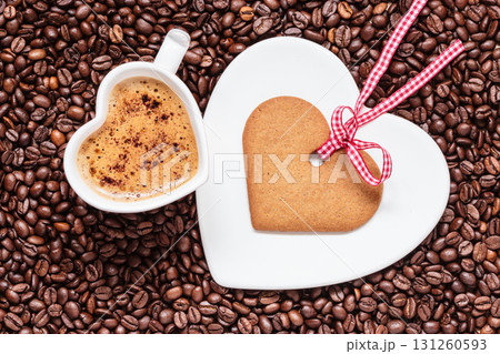 Heart shaped cup and cookie on coffee beans background Heart shaped cup and cookie on coffee beans background 131260593