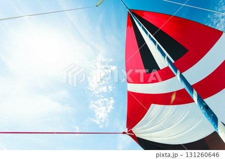 Spinnaker with uphaul, blue sky in background. Spinnaker with uphaul, blue sky in background. 131260646