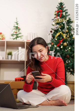 Christmas joy. Woman smiling while using smartphone for online shopping. Christmas joy. Woman smiling while using smartphone for online shopping. 131261120