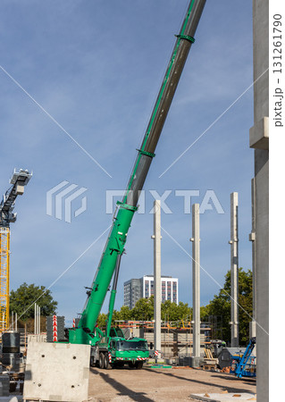 Extra heavy weight load mobile boom crane working modern city construction site with many concrete pillars blue sky background. Telescopic boom lifting equipment rental service. Industrial machinery Extra heavy weight load mobile boom crane working modern city construction site with many concrete pillars blue sky background. Telescopic boom lifting equipment rental service. Industrial machinery 131261790