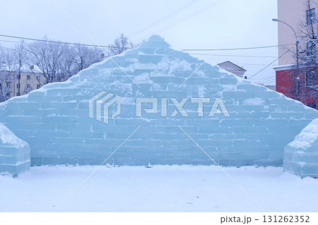 Ice brick wall in the town square. Decoration with ice figures for the holiday. 131262352