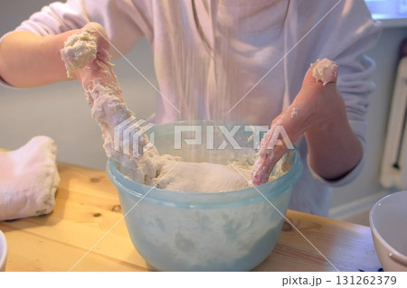 Woman kneads pizza dough in bowl. Hands close-up. Woman kneads pizza dough in bowl. Hands close-up. 131262379