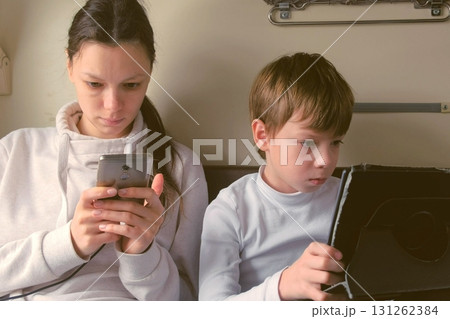 Mom and son in gadgets travelling by train is playing a games in a second-class carriage. Mom and son in gadgets travelling by train is playing a games in a second-class carriage. 131262384