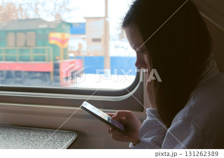 Tired young woman in train watching video in mobile phone. Tired young woman in train watching video in mobile phone. 131262389