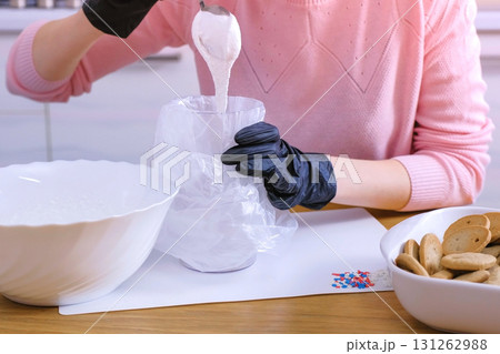 Woman's hands put the sugar sweet icing in the bag for decorating cookies and gingerbread houses. Woman's hands put the sugar sweet icing in the bag for decorating cookies and gingerbread houses. 131262988